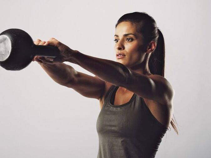 Une fille effectue un exercice pour agrandir ses seins à l’aide d’une kettlebell